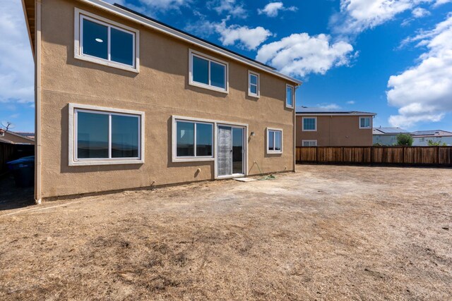 rear view of house with fence and stucco siding