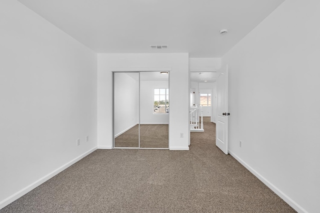 unfurnished bedroom featuring carpet floors, baseboards, and a closet