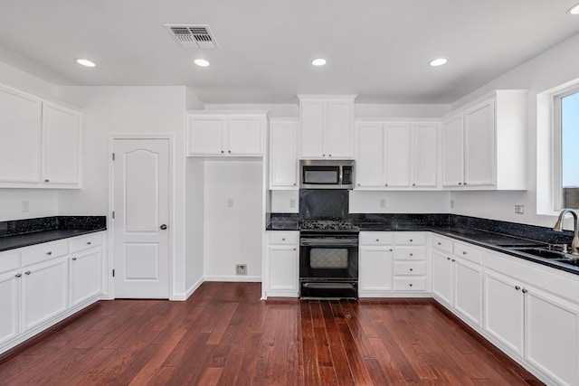kitchen featuring gas stove, stainless steel microwave, a sink, dark wood-type flooring, and white cabinetry