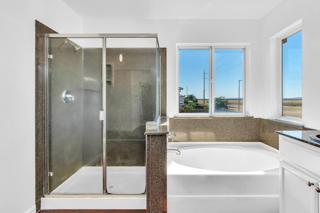 bathroom featuring a stall shower, vanity, and a bath