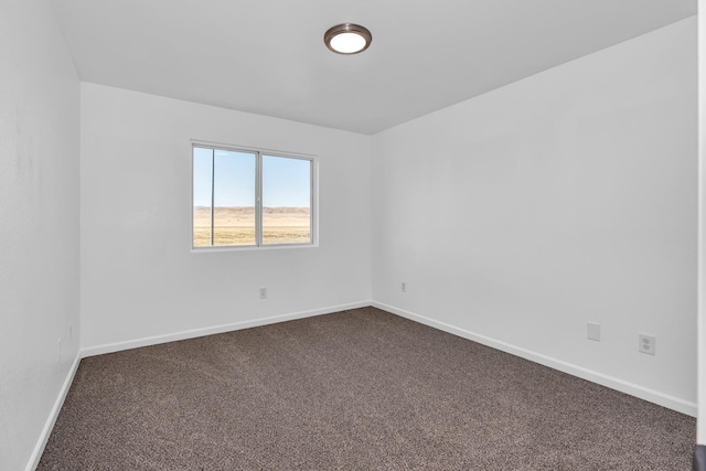 unfurnished room with dark carpet and baseboards