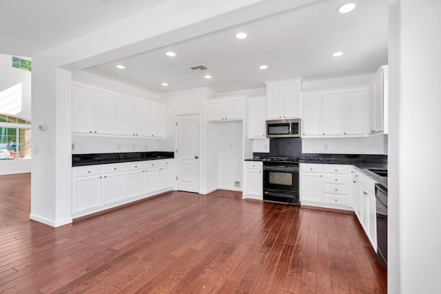 kitchen featuring black appliances, dark countertops, dark wood-style flooring, white cabinets, and recessed lighting