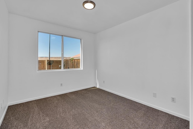 unfurnished room featuring dark colored carpet and baseboards