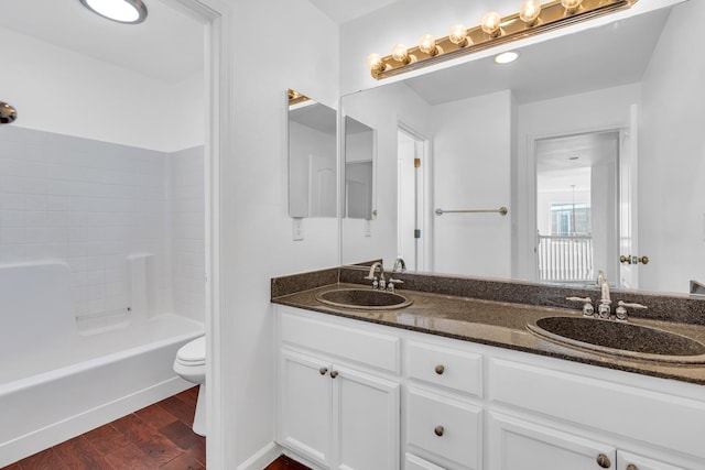 bathroom with wood finished floors, toilet, double vanity, and bathing tub / shower combination