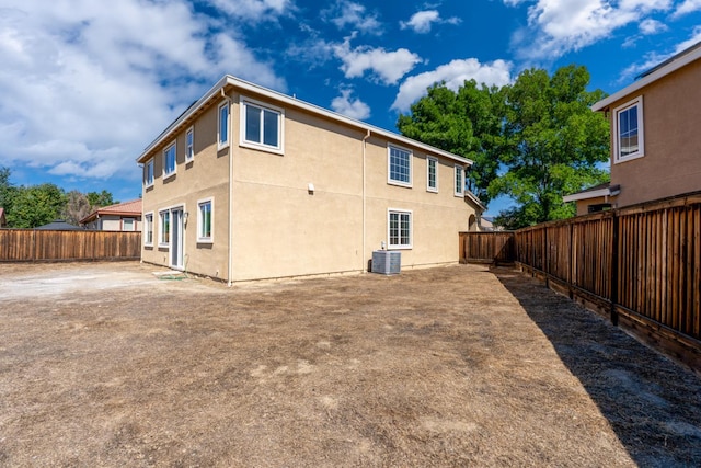 rear view of house with a fenced backyard, stucco siding, and central air condition unit
