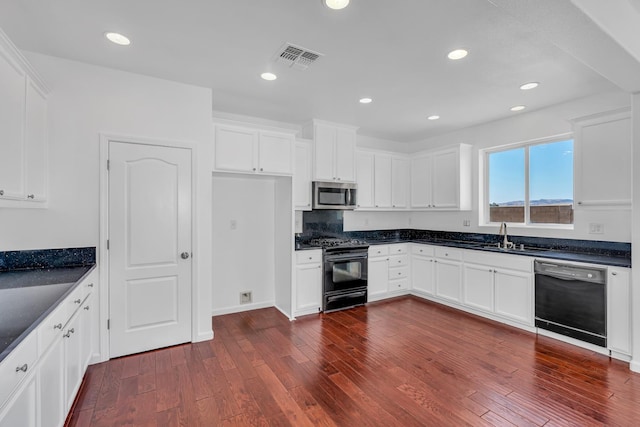 kitchen with black appliances, dark countertops, dark wood-type flooring, white cabinets, and recessed lighting