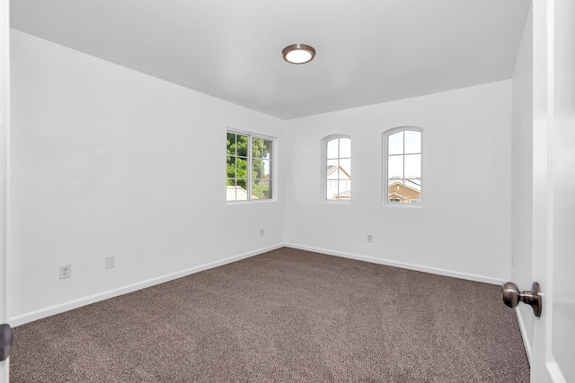 empty room with dark carpet and baseboards