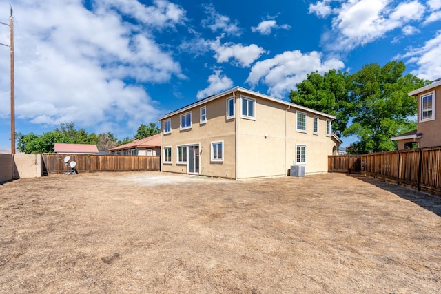 rear view of property featuring a fenced backyard, stucco siding, and central AC unit