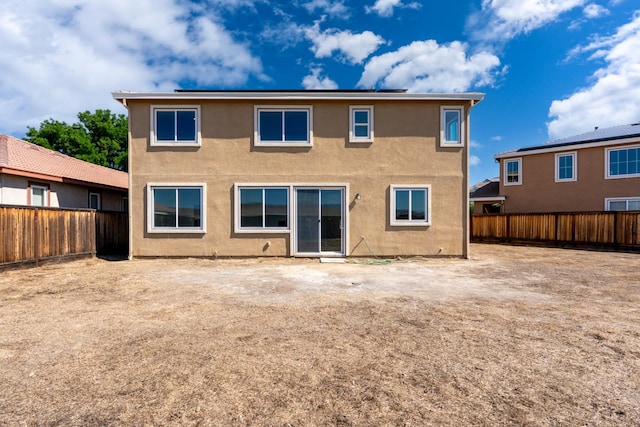 rear view of house with a fenced backyard and stucco siding