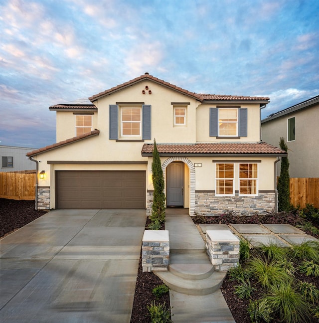 1171 Maclure Ave W, Madera, CA 93636 - mediterranean / spanish-style home featuring stone siding, fence, stucco siding, and a tile roof