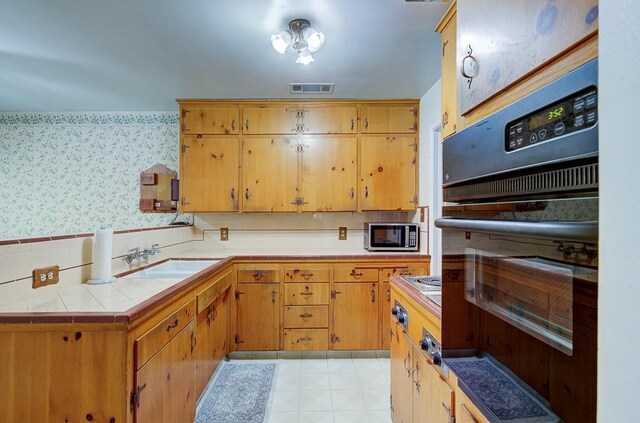 3948 E Fedora Ave, Fresno, CA 93726 - kitchen featuring oven, wallpapered walls, stainless steel microwave, and tile countertops
