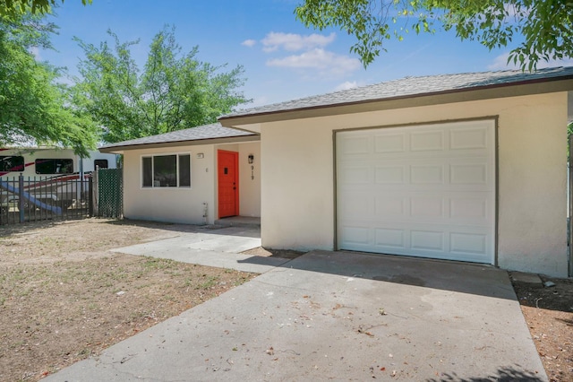 single story home featuring concrete driveway, stucco siding, fence, and an attached garage