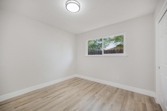 spare room featuring baseboards and light wood finished floors