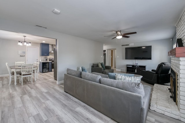 2983 E Northdale Ave, Fresno, CA 93726 - living area with ceiling fan, a brick fireplace, a chandelier, light wood-type flooring, and baseboards