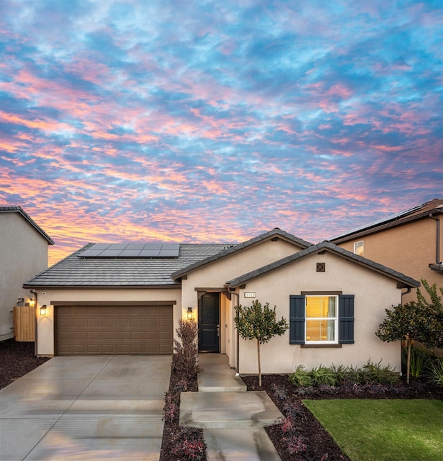 1163 Maclure Ave W, Madera, CA 93636 - view of front facade with an attached garage, concrete driveway, stucco siding, and roof mounted solar panels