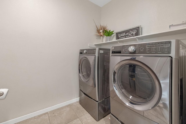 laundry area with washing machine and dryer, baseboards, and light tile patterned floors