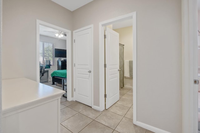 hall featuring light tile patterned flooring and baseboards