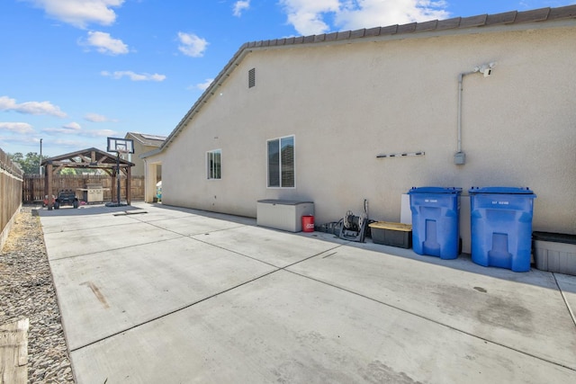 rear view of property featuring a gazebo, stucco siding, a fenced backyard, and a patio area