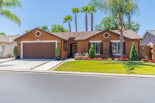 5266 E Harvest Ln, Fresno, CA 93725 - ranch-style house featuring stucco siding, a garage, driveway, a front yard, and outdoor lounge area