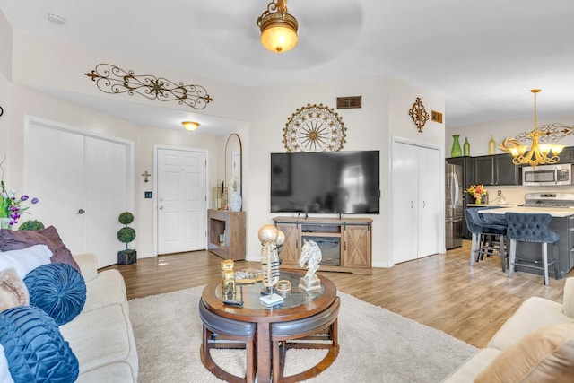 5266 E Harvest Ln, Fresno, CA 93725 - living room featuring a chandelier, light wood-style floors, and baseboards