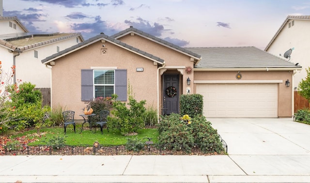 view of front of property with a garage, driveway, stucco siding, a tile roof, and a front lawn