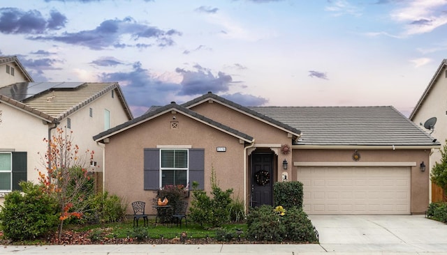 view of front of home featuring an attached garage, concrete driveway, stucco siding, and a tile roof