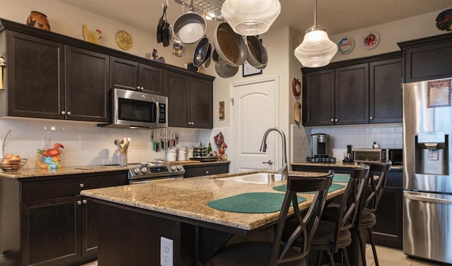kitchen with appliances with stainless steel finishes, a sink, light stone counters, and decorative backsplash