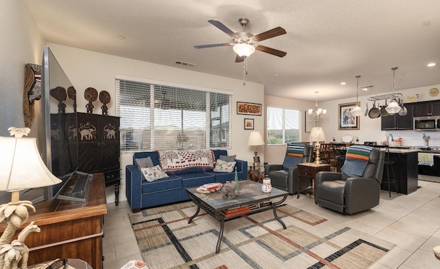 living room with a ceiling fan, a chandelier, light tile patterned floors, and recessed lighting