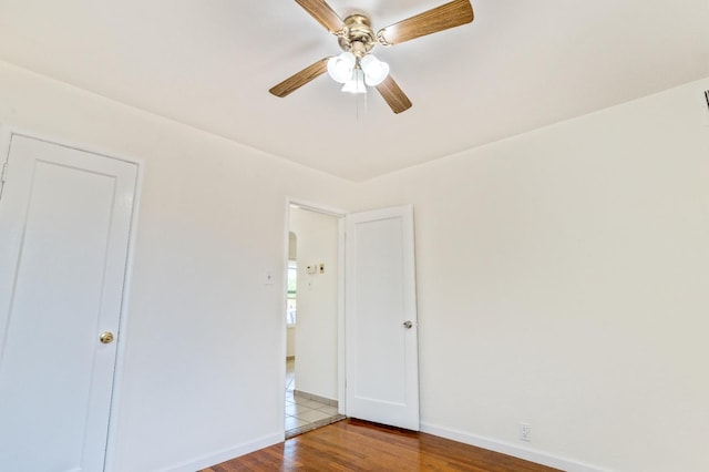 324 E San Mateo St, Avenal, CA 93204 - unfurnished bedroom featuring wood finished floors, baseboards, a ceiling fan, and arched walkways