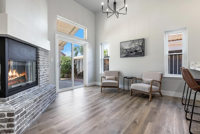 1801 E Omaha Ave, Fresno, CA 93720 - living area featuring wood finished floors, a chandelier, a brick fireplace, a towering ceiling, and baseboards