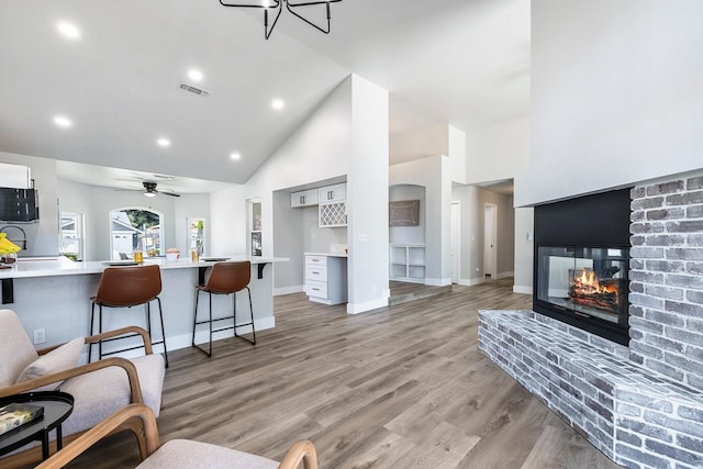 1801 E Omaha Ave, Fresno, CA 93720 - living room featuring high vaulted ceiling, baseboards, a brick fireplace, light wood-style flooring, and recessed lighting