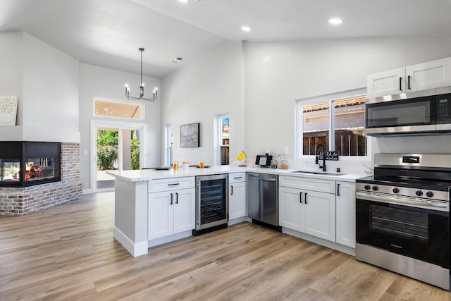 1801 E Omaha Ave, Fresno, CA 93720 - kitchen featuring stainless steel appliances, beverage cooler, a sink, a peninsula, and high vaulted ceiling