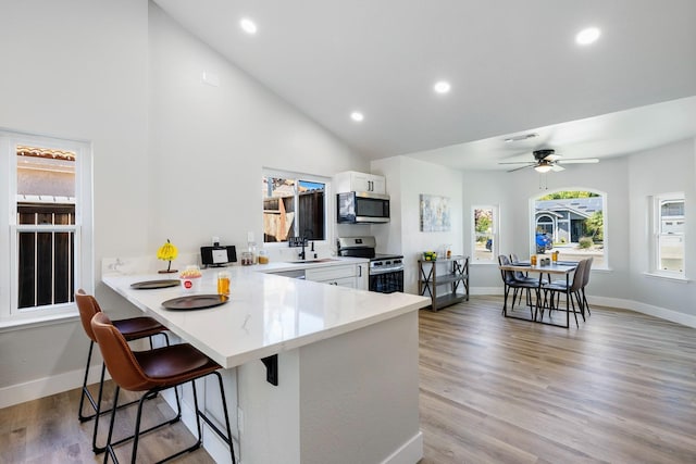 1801 E Omaha Ave, Fresno, CA 93720 - kitchen with appliances with stainless steel finishes, a breakfast bar, baseboards, white cabinetry, and a sink