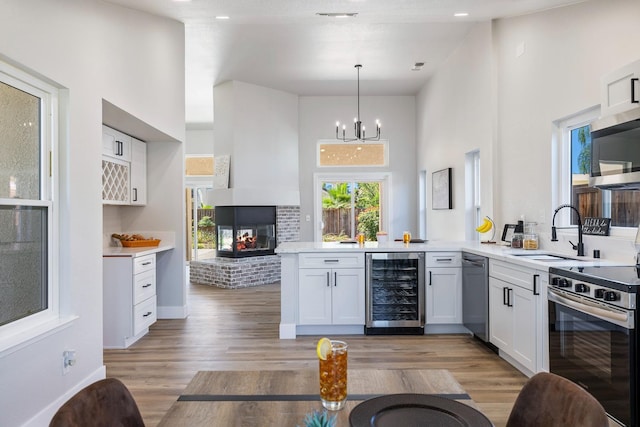 1801 E Omaha Ave, Fresno, CA 93720 - bar featuring beverage cooler, a sink, appliances with stainless steel finishes, a brick fireplace, and light wood-type flooring