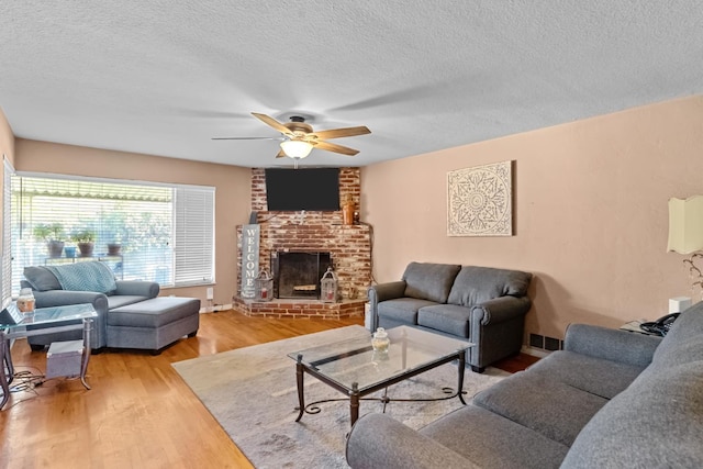 3356 E Austin Way, Fresno, CA 93726 - living area featuring light wood-style floors, ceiling fan, a textured ceiling, and a brick fireplace