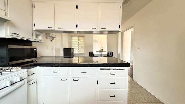 1380 Elaine Dr, Hanford, CA 93230 - kitchen with a peninsula, stainless steel microwave, dark countertops, and white cabinets
