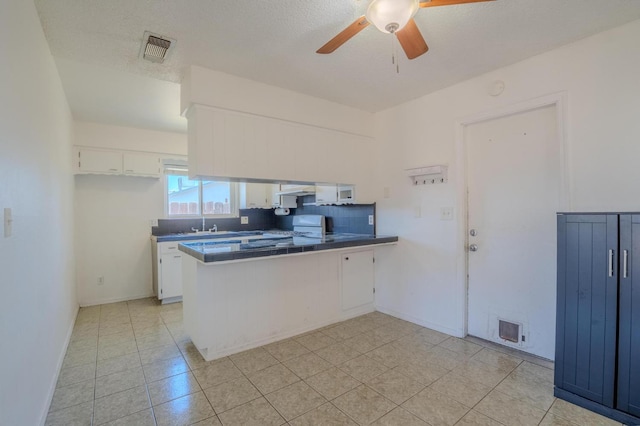 1380 Elaine Dr, Hanford, CA 93230 - kitchen with a peninsula, dark countertops, white cabinetry, ceiling fan, and tasteful backsplash
