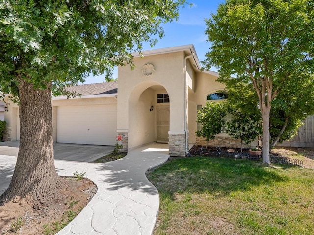 5611 W Carmen Ave, Fresno, CA 93722 - mediterranean / spanish-style home with stucco siding, a garage, concrete driveway, and stone siding