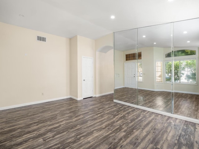 5611 W Carmen Ave, Fresno, CA 93722 - unfurnished room featuring dark wood-style floors, baseboards, recessed lighting, arched walkways, and vaulted ceiling