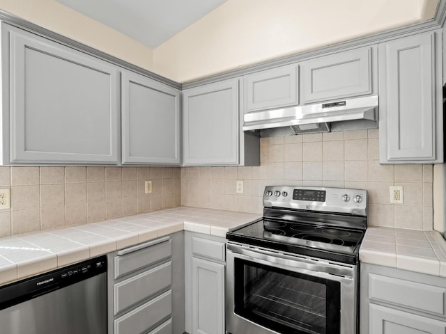 5611 W Carmen Ave, Fresno, CA 93722 - kitchen featuring appliances with stainless steel finishes, under cabinet range hood, tile counters, and tasteful backsplash