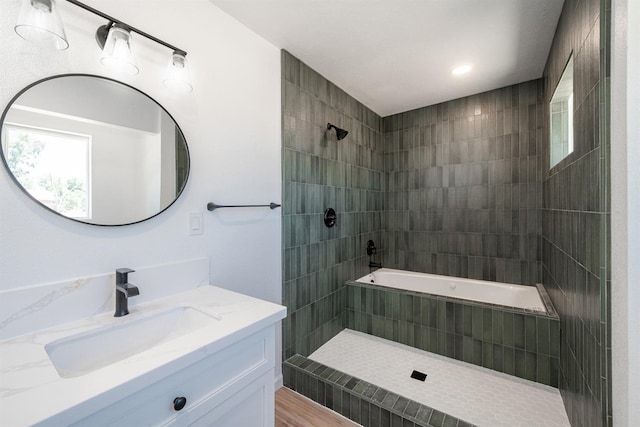 full bath with tiled shower, vanity, and wood finished floors