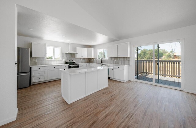 15758 Mark Rd, Madera, CA 93636 - kitchen with wall chimney exhaust hood, appliances with stainless steel finishes, light wood-type flooring, backsplash, and vaulted ceiling