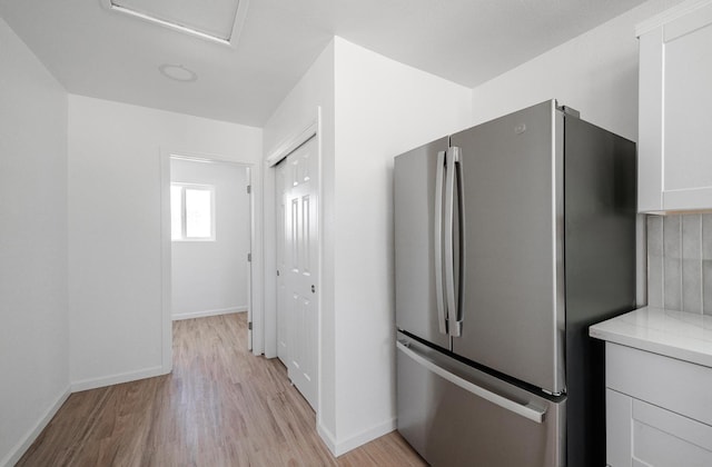 15758 Mark Rd, Madera, CA 93636 - kitchen with freestanding refrigerator, light countertops, light wood-style flooring, white cabinets, and tasteful backsplash