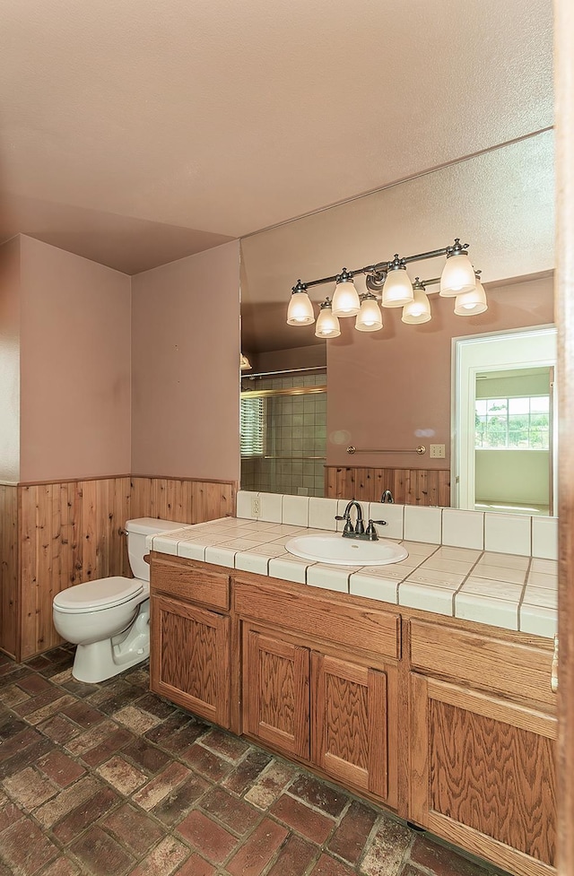15501 Garlock Ln, Prather, CA 93651 - full bath featuring a stall shower, a wainscoted wall, brick flooring, toilet, and wooden walls