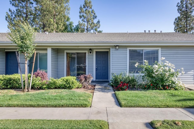 ranch-style house with a shingled roof and a front yard