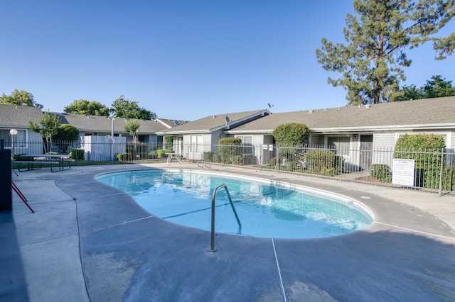 community pool featuring fence, a patio area, and a residential view