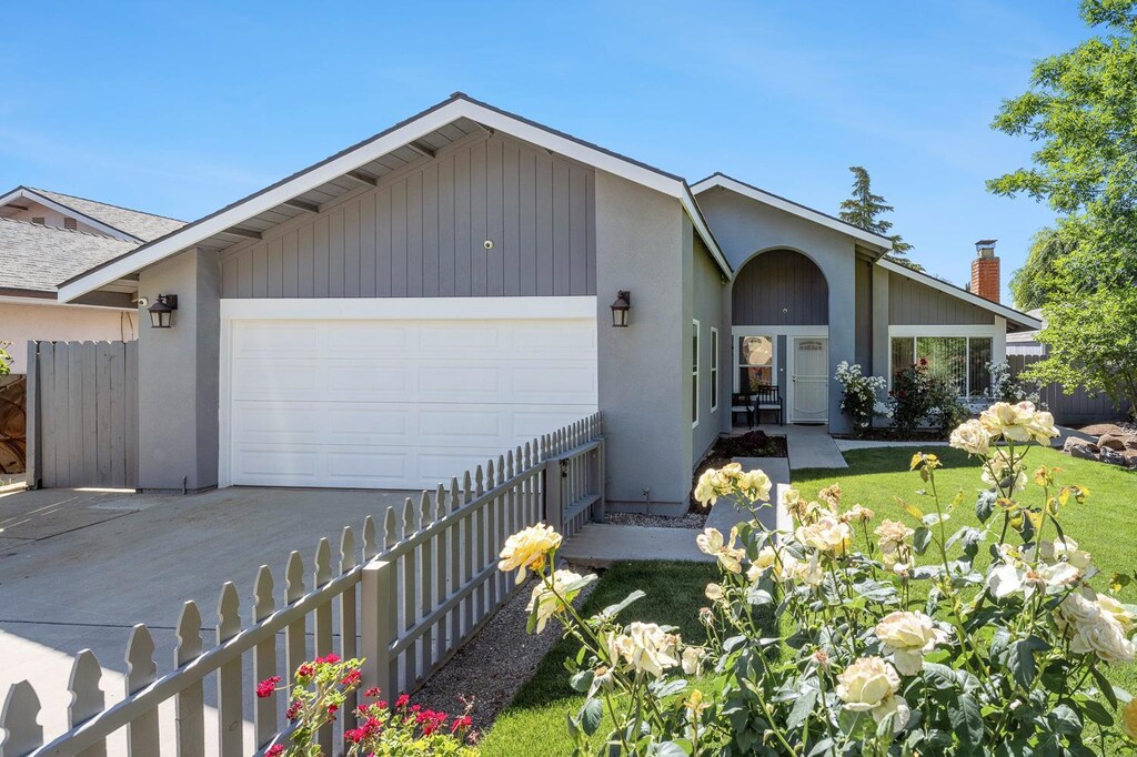 5298 N Reese Ave, Fresno, CA 93722 - view of front of home featuring an attached garage, driveway, fence, stucco siding, and a chimney
