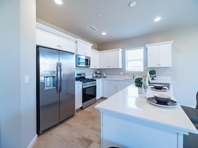 873 Beaver Pond Loop, Madera, CA 93636 - kitchen featuring appliances with stainless steel finishes, white cabinets, recessed lighting, light stone countertops, and a kitchen island