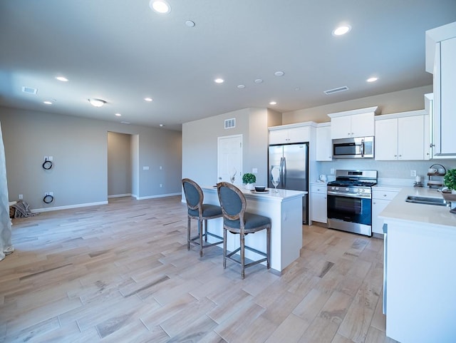 873 Beaver Pond Loop, Madera, CA 93636 - kitchen with stainless steel appliances, a sink, a kitchen island, a breakfast bar, and light wood-type flooring