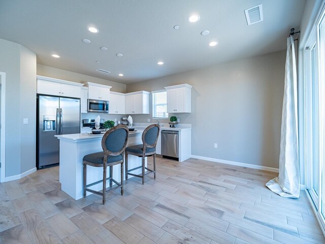 873 Beaver Pond Loop, Madera, CA 93636 - kitchen featuring appliances with stainless steel finishes, an island with sink, a kitchen bar, white cabinets, and light countertops